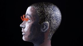 Beauty afro woman face painted mannequin with brown eyes and orange eye lashes, on black background. Slowly moving ebony female model care treatment or cosmetic ads concept idea, not a real human. - Powered by Shutterstock - Get 15% off with code: PIKWIZARD15