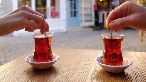 Stirring sugar with a spoon in a glass of Turkish tea in slow motion. Drinking tea in outdoor cafe in Turkey