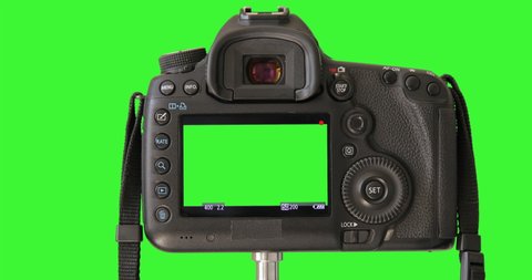 DSLD camera isolated on keyed green screen recording video. Professional digital camera standing on tripod. Closeup LCD monitor. Shooting Process. Camera settings is showing on the screen.