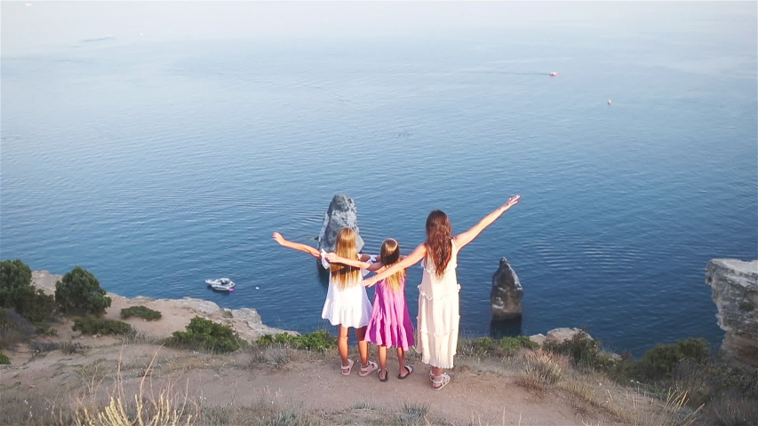 Mother with kids on the beach enjoying summer. Family vacation on the cliff