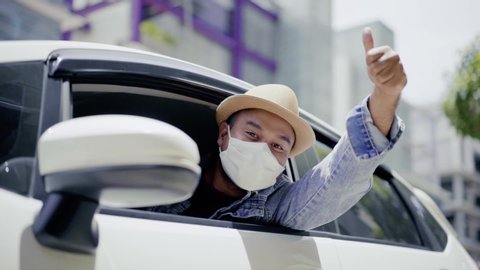 Young asian backpacker traveling in urban city, He wearing face mask for protect virus air pollution on safety travel, He thumb up when he inside the car. Slow Motion Shot.
