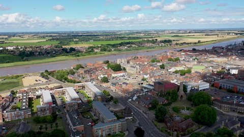 Aerial footage of the beautiful town of King's Lynn a seaport and market town in Norfolk, England UK showing the main town centre along side the River Great Ouse on a sunny summers day with clouds