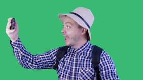 Portrait of friendly cheerful funny guy recording video blog taking making selfie isolated on green background. Chroma Key. Travel, tourism, hike, technology and people concept