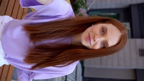 Portrait of redhead lady welcoming person on phone during online video chat on background of city street. Vertical orientation video of young woman communicating through video chat using cellphone. - Powered by Shutterstock - Get 15% off with code: PIKWIZARD15