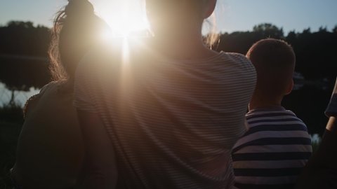 Video of family relaxing by the lake during sunset. Shot with RED helium camera in 8K.  Video de stock