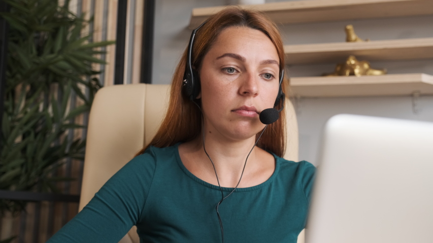 Service phone operators. Agent woman in headset use pc answers incoming calls talk with client provide at home Royalty-Free Stock Footage #1056958376