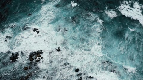 Impressive aerial video of powerful waves crashing at rocky cliffs and splashing white foam. Scenic top aerial view of teal ocean. Cinematic 4K drone nature video. Outdoor adventure and background. 