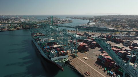 Port San Pedro, February 2020. Long Beach, Los Angeles, California, USA. The view of container cranes operating in harbor on lifting containers from the deck of a freighter, moored at a dock on water