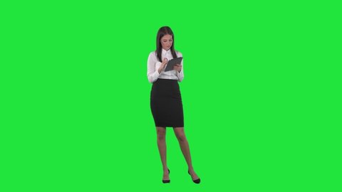 Happy relaxed young business woman employee working on tablet touch screen. Full length on green screen background.	