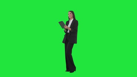 Side view of young business woman working on tablet using interactive touch screen. Full length on green screen background
