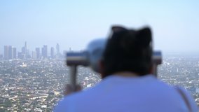 Woman looking at downtown in Los Angeles using binoculars in 4k slow motion 60fps