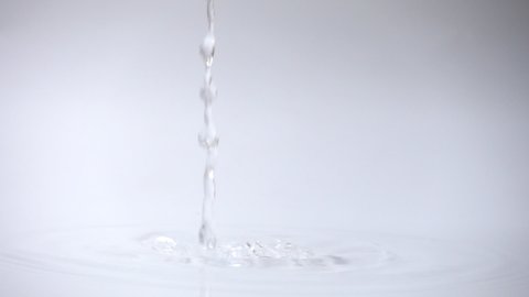 Pour water to water surface in container over white background in slow motion.
