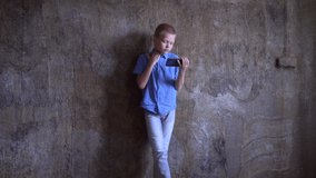 teenage boy in blue shirt and gray jeans plays professionally on smartphone with large screen. Child devotes lot of time to game and perceives victory or defeat very emotionally