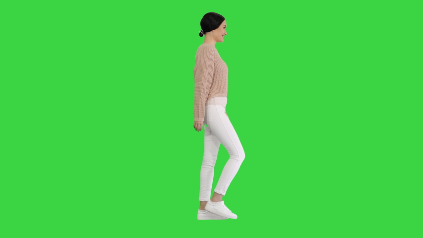Relaxed young woman walking towards and looking with smile at camera in casual style clothes on a Green Screen, Chroma Key. Royalty-Free Stock Footage #1056968171