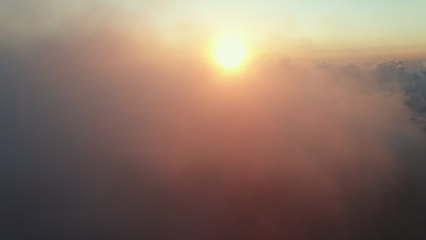 Moving white clouds blue sky scenic aerial view sunrise. Drone flies high back in blue sky through fluffy clouds in morning at orange sun summer. Sun is hidden behind clouds at fog. Relax. Nature Royalty-Free Stock Footage #1056969149