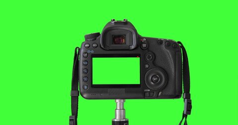 DSLD camera isolated on keyed green screen recording video. Professional digital camera standing on tripod. Closeup LCD monitor. Shooting Process.