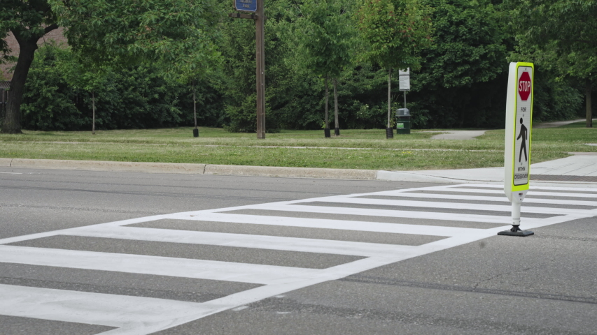 father and son wearing shorts and sandals cross street at cross walk while holding hands then a car passes