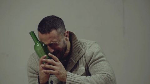 Alcoholism, alcohol addiction and people concept - male alcoholic with bottle drunk. Crying man with alcoholic drink, emotional portrait
