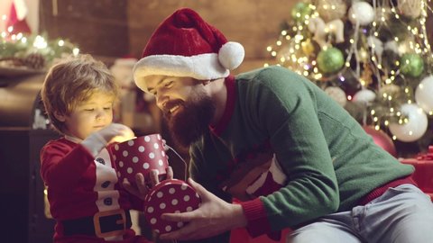 Cute child son open Christmas gift from his father. Santa plays with kid. Father and son packing xmas gifts. Dad and son giving presents at home