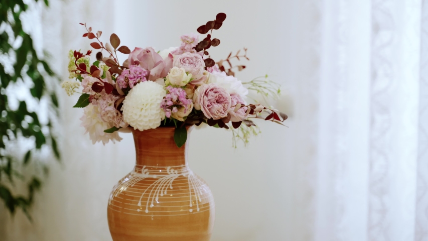 A bouquet of pink flowers in a vintage vase on the table | Shutterstock HD Video #1056976067