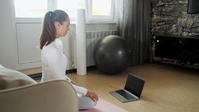 sporty girl with ponytail in white tracksuit watches video of new training on modern laptop