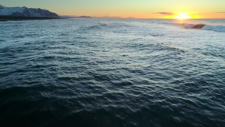 Flying over the Ocean during golden hour. Giant waves foaming and splashing in the ocean Royalty-Free Stock Footage #1056977762