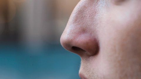 Detail shot of a man's nose against a defocused city background. Slow motion