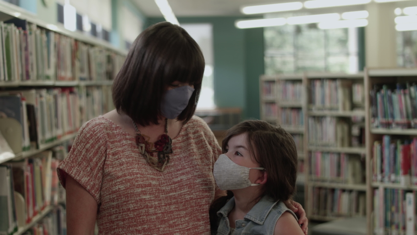 Mom and daughter with masks in library