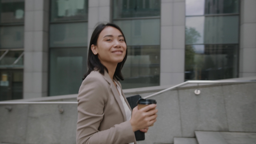 Young rich successful businesswoman walks upstairs with coffee to enter office building working in beautiful modern business center. Royalty-Free Stock Footage #1056986468