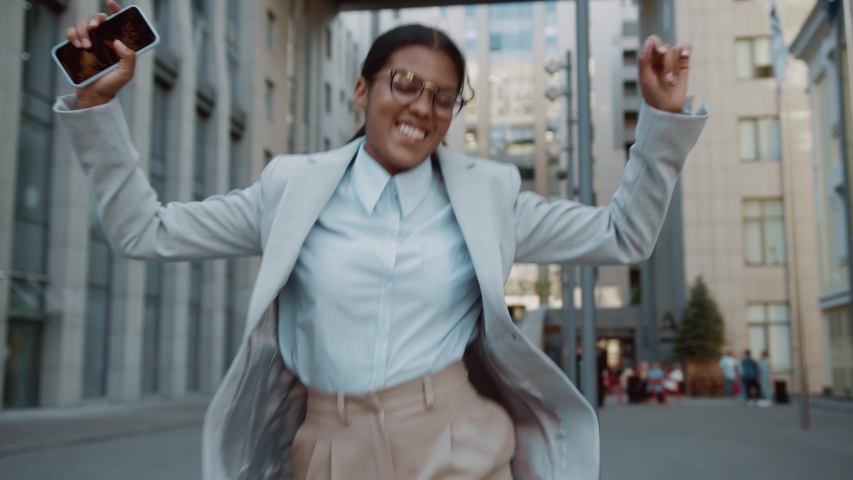 Happy excited businesswoman young entrepreneur celebrating victory dancing with smartphone on street having fun enjoy job opportunities. Career people. Celebration. Royalty-Free Stock Footage #1056986498