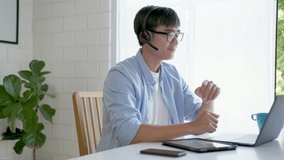 Medium shot : Asian man in casual shirt sitting telework or webinar on laptop computer. Businessman video conference using laptop and tablet online meeting.Working from home and Working remotely.