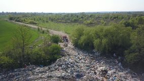 A garbage truck arrives at a natural landfill. People dump waste at the entrance. Aerial video.