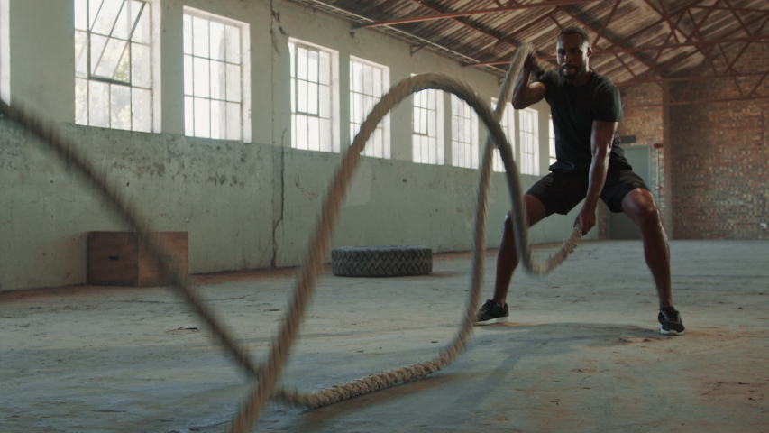 Fitness man exercising with battle rope abandoned warehouse. Tough man working out in cross training gym made inside old factory.
 Royalty-Free Stock Footage #1056988955