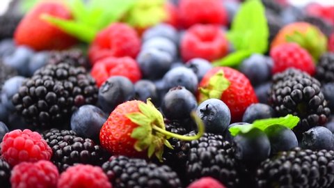 Berries. Various colorful berries rotation background. Mint leaves, Strawberry, Raspberry, Blackberry, Blueberry close-up rotating backdrop. Fresh Bio Fruits, Healthy eating, diet. 4K UHD video