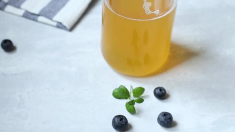 Drink cold, healthy, homemade fermented kombucha with natural probiotic properties. Drink with ice in a glass bowl on a light background.