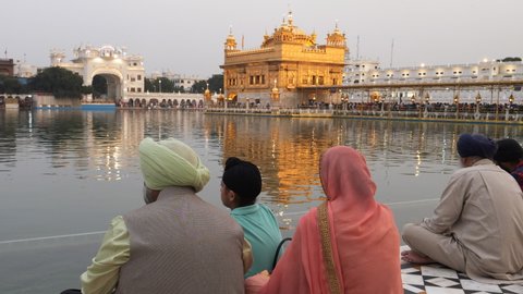 AMRITSAR, INDIA - MARCH 18, 2019: sikh family sitting by pool at golden temple in amritsar, india