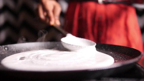 Closeup slow motion view of steaming hot 'Dosa' on a nonstick pan. Dosa is the Indian version of pancake made with rice flour dough