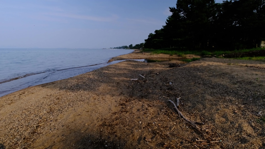 Beautiful view of sandy beach and cloudy horizon with long afternoon shadows. Sandy beach on beautiful lake without people. Summer time. Summer weather.