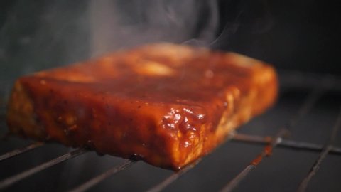 Closeup of a cottage cheese steak being barbecued on a grill with dramatic smoke