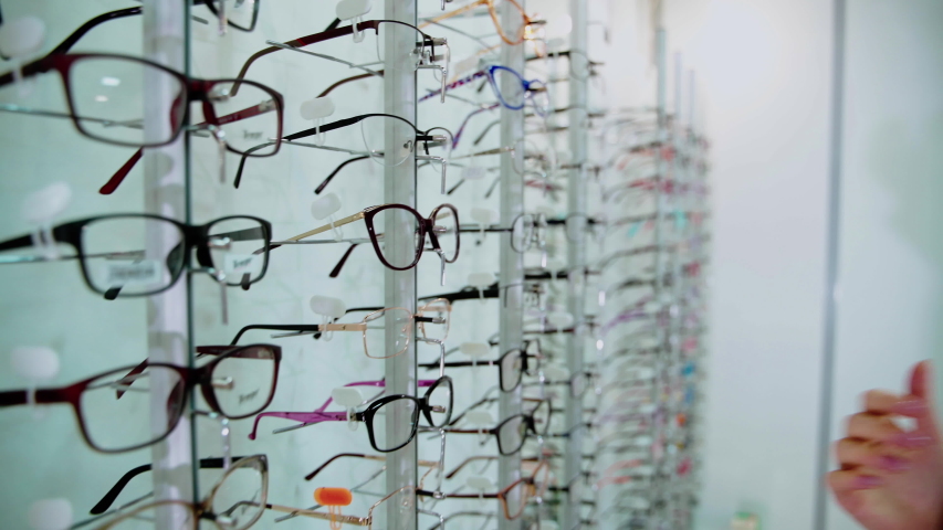 Young woman is choosing a glasses in optician store. Royalty-Free Stock Footage #1057005038