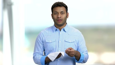 Young Indian man about to sneeze. Sneezing man on blurred background. Flu or allergy symptoms.