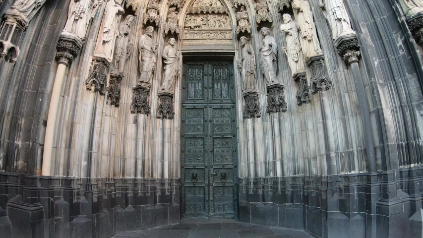 SLOW SHOT Entrance of the Cologne Cathedral (Kolner Dom), Roman Catholic cathedral, located in the city of Cologne, Germany, shows the 19th century decoration. Marble figures of saints on the facade.