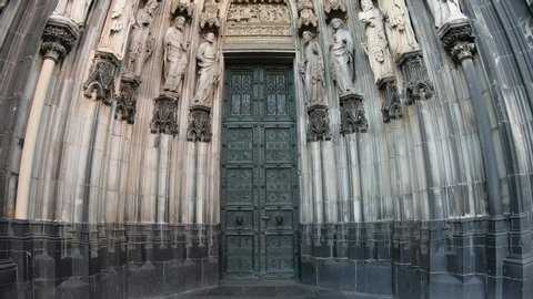SLOW SHOT Entrance of the Cologne Cathedral (Kolner Dom), Roman Catholic cathedral, located in the city of Cologne, Germany, shows the 19th century decoration. Marble figures of saints on the facade.