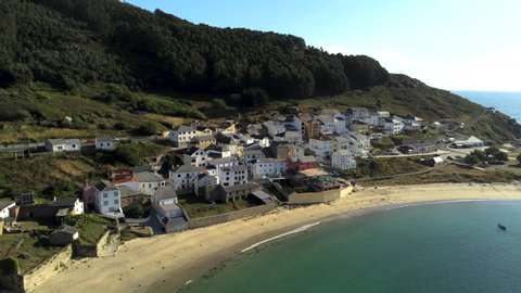 Panning drone shot of beach and town Puerto de Bares, Galicia from mountains to ocean