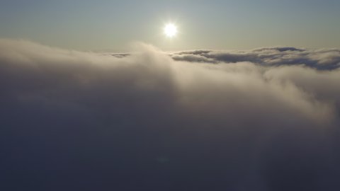 Rapid flight through heavenly beautiful sunny cloudscape at sunrise. Amazing golden clouds moving rapidly on the sky and the sun shining through the fluffy mist. 4K b roll drone footage, time lapse