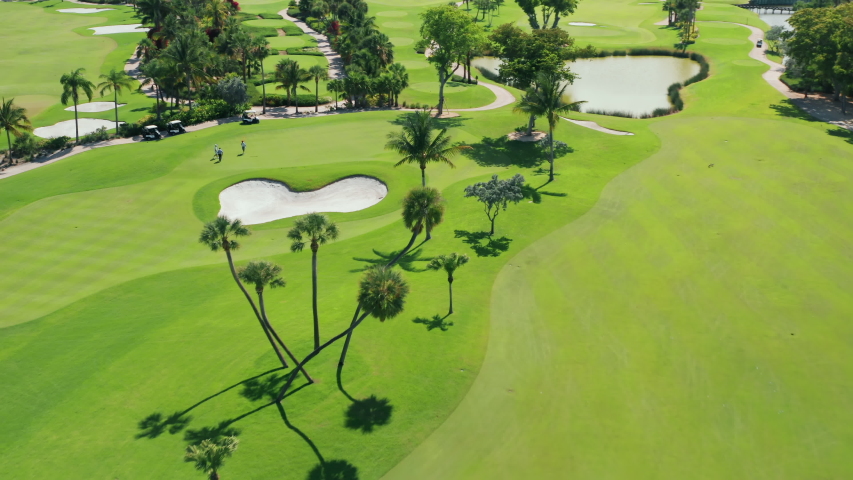 Cinematic overhead view on active men playing the golf game on a sunny summer day. Aerial footage of people on a golf course playing the sport match in Miami, Florida, USA. Background for business Royalty-Free Stock Footage #1057011329