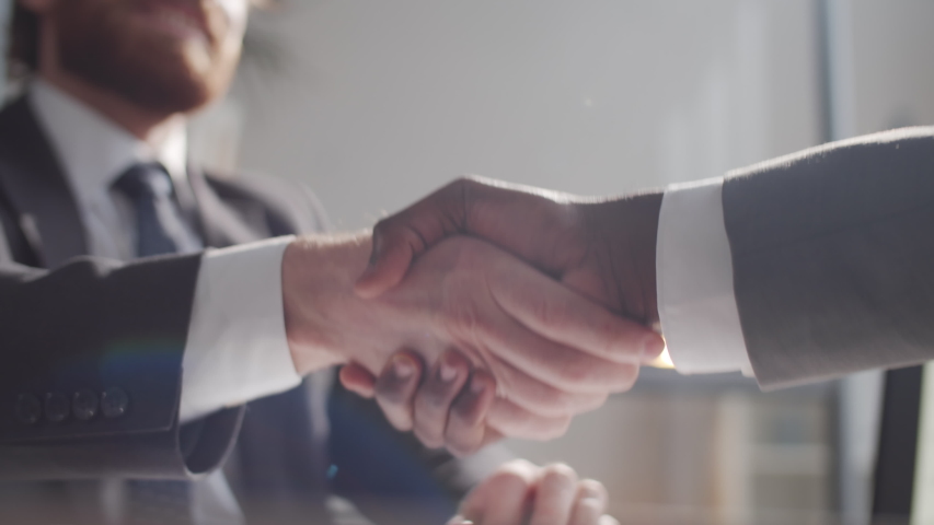 Close up selective focus shot of handshake of two multiethnic business partners in formalwear during meeting in the office. Royalty-Free Stock Footage #1057012790
