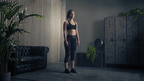 Woman exercising at home.Woman doing fitness legs training at home. Woman doing jumping jacks. Industrial style house. Bodycare,determination. Static tripod shot