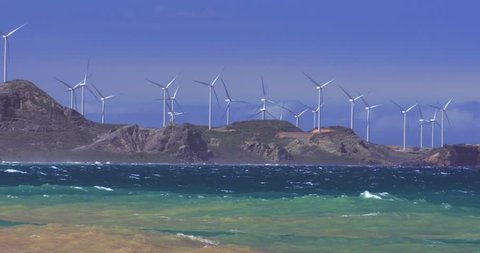 Panoramic view of sea coast with many wind mill turbines installed along shore at clear day 