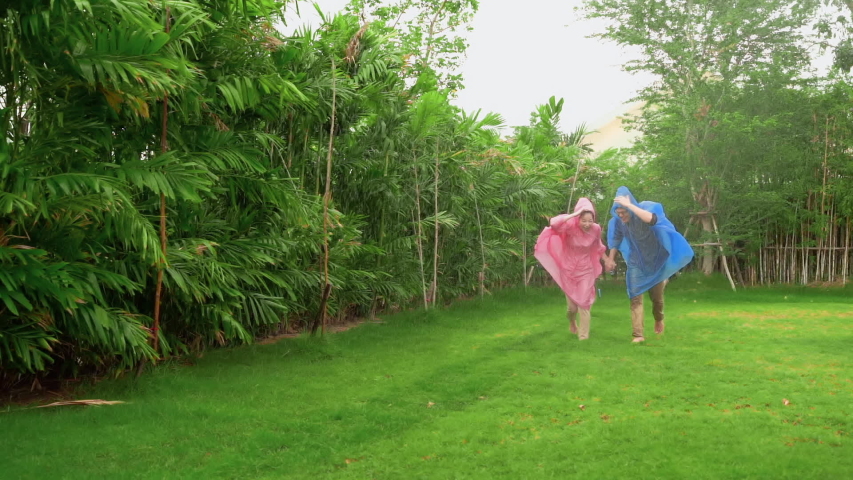 Couples who wear raincoats are having fun playing on the grass in the backyard.
